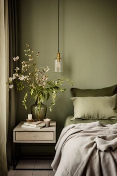 a bedroom with green walls and white flowers in a vase on the nightstand next to the bed