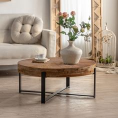 a coffee table with flowers in a vase on it and a birdcage next to it