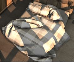 an unmade bed with plaid sheets and pillows