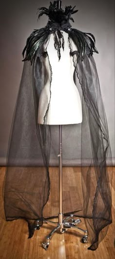 a mannequin wearing a black veil on top of a wooden floor