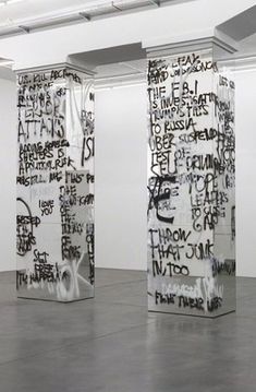 three tall white pillars covered in black and white graffiti