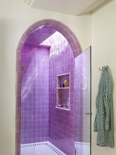 a bathroom with purple tile walls and a shower stall in the corner, next to a white tiled floor