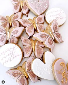 cookies decorated with pink and gold butterflies are on a table next to a white heart