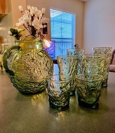 four glasses and a pitcher sitting on a counter