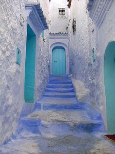 an alley way with blue steps and white walls