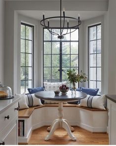 a dining room table and bench in front of large windows