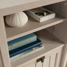 a book shelf with some books on it and a white vase sitting next to it