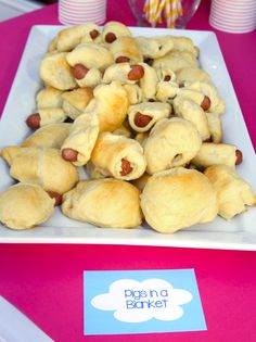 a plate full of pigs in a blanket on top of a table with candy sticks