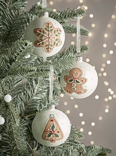 christmas ornaments hanging from a tree with lights in the background