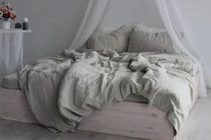 an unmade bed with white linens and pillows on top of it in a bedroom