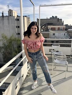 a woman standing on top of a roof next to a chair