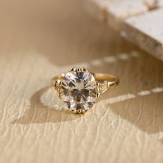 a close up of a diamond ring on a piece of paper with a book in the background