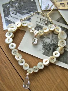 a necklace made out of buttons on top of a wooden table next to an old photo