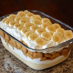 a dessert dish with banana slices and whipped cream in it on a marble countertop