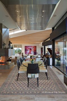 the dining room table is surrounded by black chairs and an area rug that matches with the fireplace