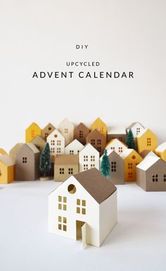 a small white house sitting in front of a row of houses with the words diy upcycled advent calendar written above it