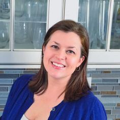 a woman is smiling for the camera in front of some cupboards and glassware