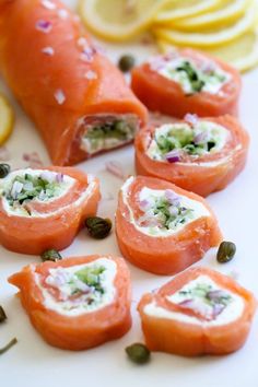 salmon and capers wrapped in cream cheese on a white plate with lemon wedges