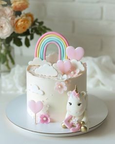 a white cake with pink and blue icing on it, topped with a unicorn figurine