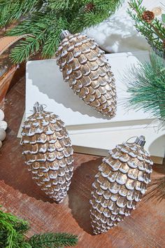 three silver pine cones sitting on top of a wooden table