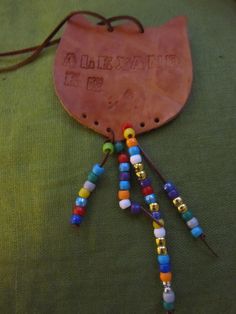 a leather bag with beads hanging from it's side on a green cloth covered floor