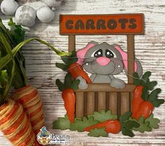 carrots and a potted plant are sitting on a table next to a sign that says carrots