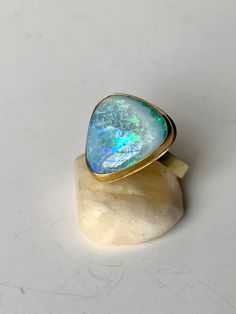 Stunning Australian Boulder Opal wrapped in a 22k Gold bezel sitting upon a wide 4mm 18k Gold band. This opulent ring is ready to make a statement on any finger!  The Opal is 17mm x 17mm. Size 6 3.4. Wide Band Ring Opal, Luxury Handmade Opal Ring, Australian Opal Ring Capucinne, Luxury Modern Opal Ring, Opal Ring Thick Band, Handmade Luxury Opal Ring, Modern Luxury Cabochon Opal Ring, Modern Luxury Opal Cabochon Ring, 22k Gold Earrings