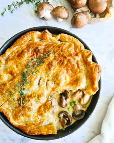 an omelet with mushrooms and herbs in a skillet on a marble counter