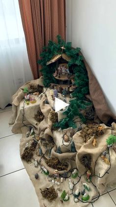 a nativity scene made out of burlocked fabric and fake trees on the floor