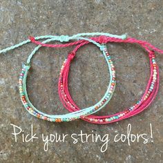 three bracelets with different colored cords on top of a stone surface that says pick your string colors