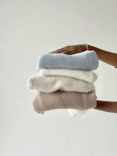 someone is holding three different sweaters in their hands, each with a white and light blue color