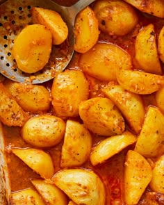 cooked potatoes with sauce in a casserole dish next to a spoon on the side