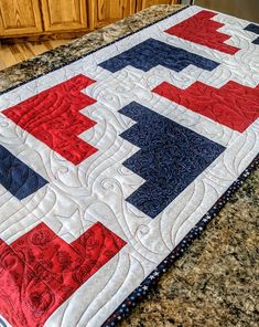 a red, white and blue quilt sitting on top of a counter next to a wooden cabinet