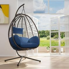 a hanging chair with blue cushions in an empty room