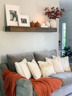 a couch with pillows and blankets on it in a living room next to a potted plant