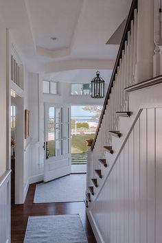 an entry way leading to a house with white walls and wood floors, along with a blue rug on the floor