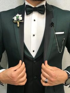 a man in a tuxedo and bow tie with his hands on his chest