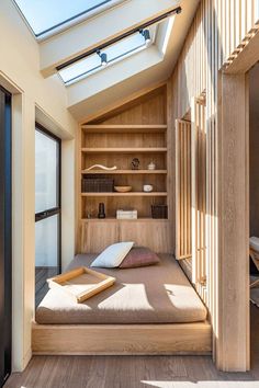 a bed sitting under a skylight in a bedroom next to a wooden shelf filled with books