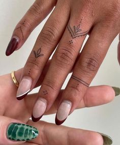 two fingers with different designs on them and one has a green leaf tattoo on it