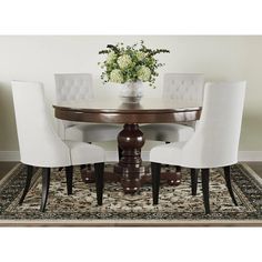 a dining room table with white chairs and a floral centerpiece on top of it