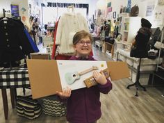 a woman holding up a cardboard box with a corkscrew on it in a store