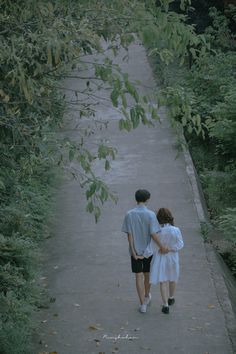 two people walking down a path in the woods