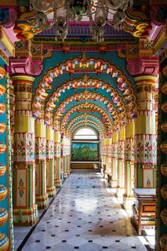 an ornate hallway with colorful columns and chandelier hanging from it's ceiling