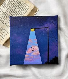 an open book sitting on top of a bed next to a lamp post and telephone pole