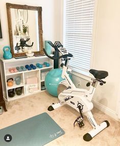 an exercise bike sits in the corner of a room with a mirror and yoga mat