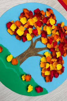 a paper plate that has a tree on it with fall leaves in the shape of a heart