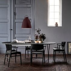 a dining room table with chairs and a lamp hanging from it's center point