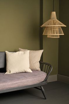 a couch with two pillows on it next to a lamp and some lightshades