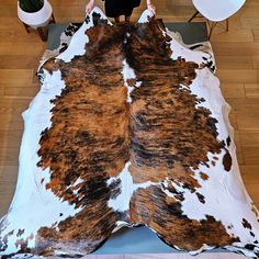 a woman standing on top of a brown and white cow skin rug