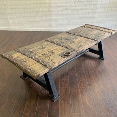 an old wooden bench with metal studs on the bottom and sides sitting on a hard wood floor